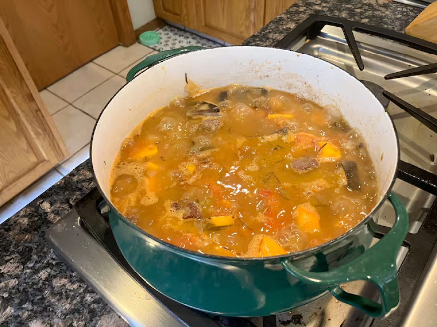 A venison stew made with salvaged roadkill in a pot on s stove burner.