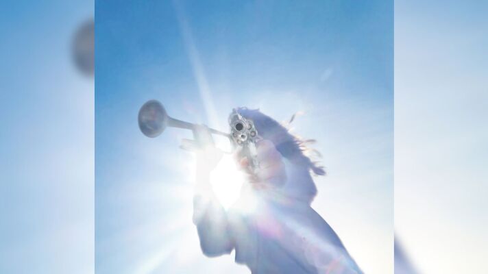 A photo from the ground looking up at a blue sky with a person pointing a gun at the camera.