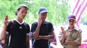 Members of Troop 2690 give the Scout sign and salute. (Gabriel Kramer/WCPN ideastream)