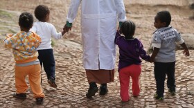 A woman walks with children at an orphanage in Addis Ababa, Ethiopia. Policymakers have long called for orphans to be taken out of institutions and placed with foster families, but one study from Duke University is challenging that notion.