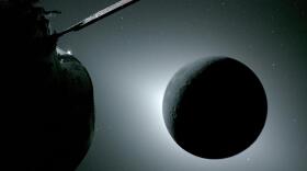 The Moon, seen here backlit by the Sun during a solar eclipse on April 6, 2026, is photographed by one of the cameras on the Orion spacecraft’s solar array wings. Orion is visible in the foreground on the left. Earth is reflecting sunlight at the left edge of the Moon, which is slightly brighter than the rest of the disk. The bright spot visible just below the Moon’s bottom right edge is Saturn. Beyond that, the bright spot at the right edge of the image is Mars.