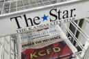 A newspaper sits flat in a wire rack inside a grocery store. The metal rack has a label that reads: "The Star."