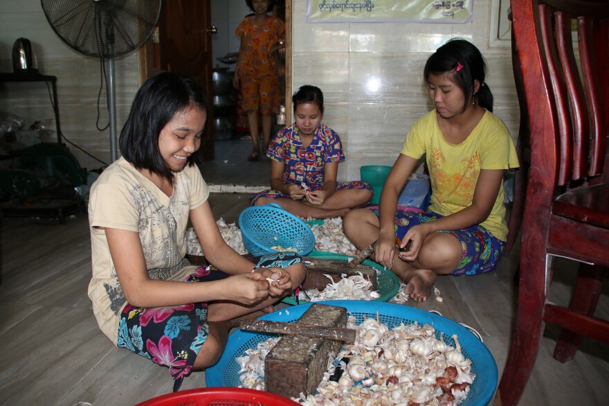 Girls prepare garlic to go in the mohinga at a Myaungmya Daw Cho restaurant in Yangon.