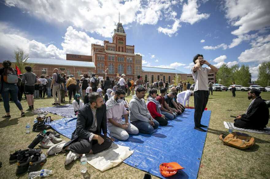 Men pray while police arrest protesters nearby.