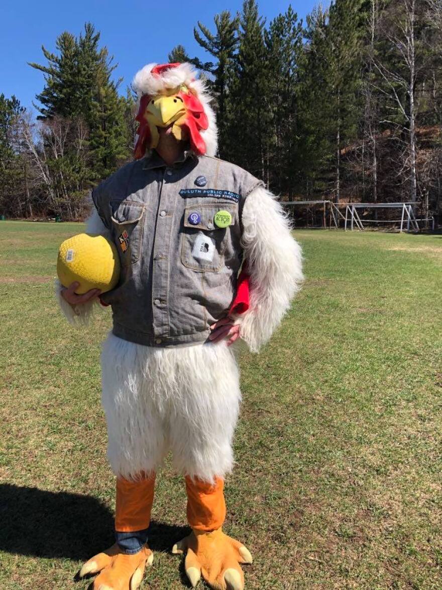 A man in a chicken costume holding a kickball