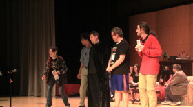 Cast members rehearse on stage inside a theater.   