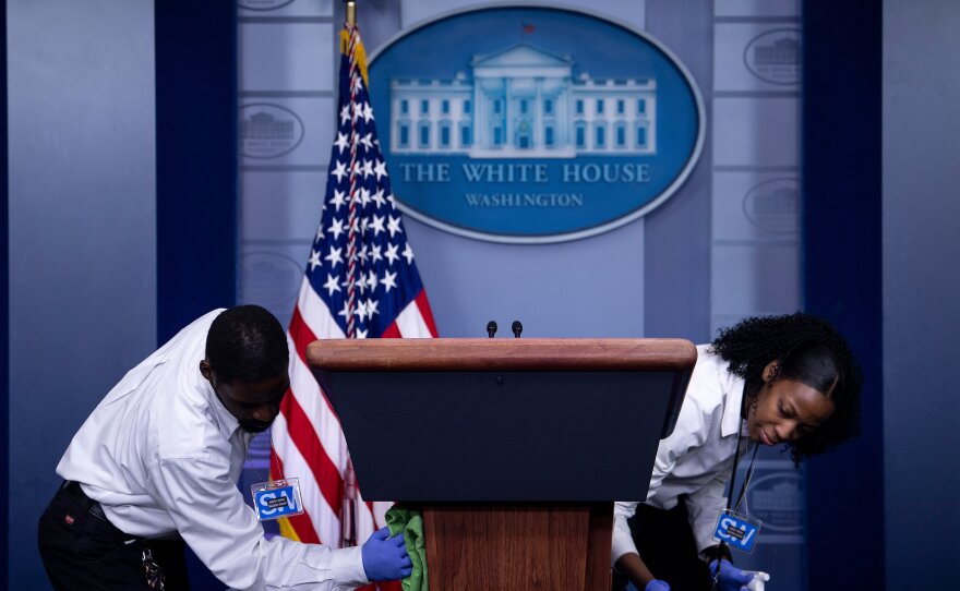 Cleaners sanitize the lectern in the White House briefing room after a coronavirus briefing on March 16, the day Trump announced his 15-day guidelines.