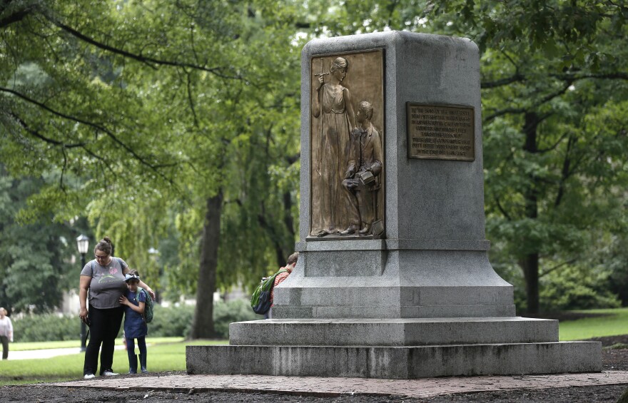 People gather near the remaining monument following a Monday night rally where the Confederate statue known as Silent Sam was toppled from it's pedestal by protesters at the University of North Carolina in Chapel Hill, N.C., Tuesday, Aug. 21, 2018. 