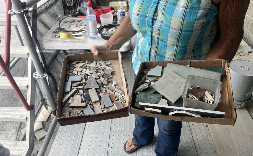Artist Terry Purdy-Arena holds boxes of the many pieces of tile used to create a mosaic mural in Montrose.