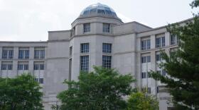  Detail view of a dome and the curved stone walls of the Michigan Supreme Court, with treetops in the foreground