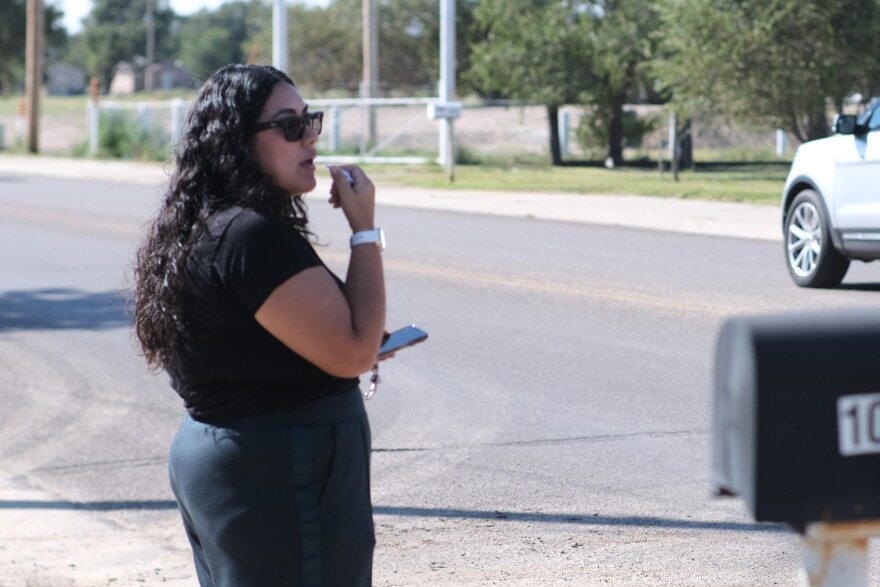 A woman stands beside the street leading to National Beef Tuesday, blowing a whistle and warning workers of federal immigration agents.