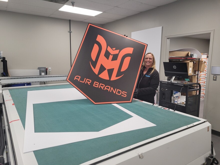 AJR Brands employee Stephanie Roark displaying a sign printed on the company's inkjet printer. 