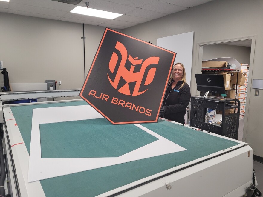 AJR Brands employee Stephanie Roark displaying a sign printed on the company's inkjet printer. &#13;
