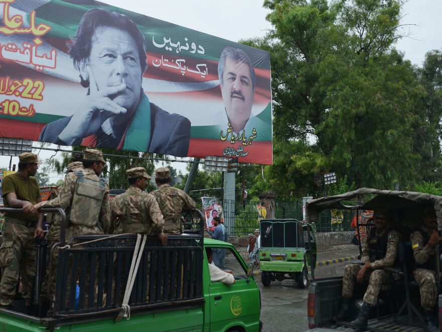 Pakistani soldiers patrol on a street beside a billboard featuring an image of Imran Khan of the Pakistan Tehreek-e-Insaf (Movement for Justice), in Rawalpindi.