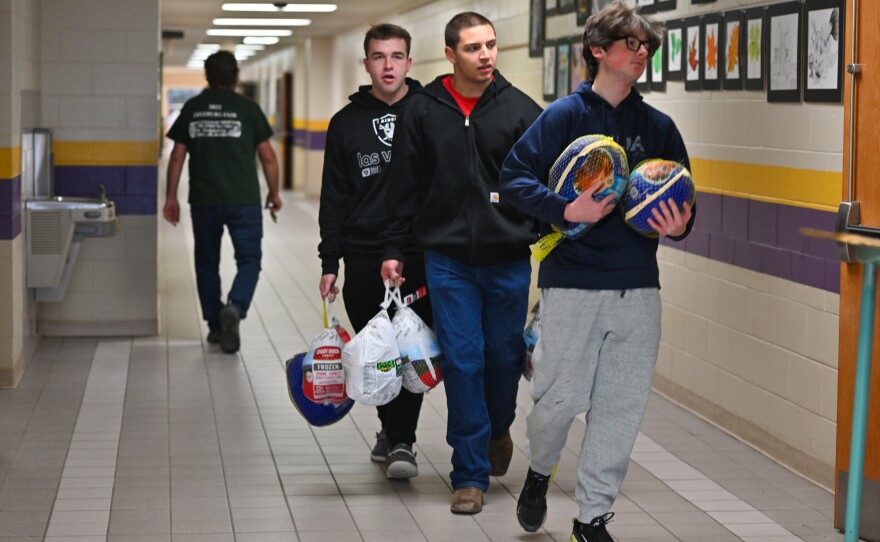 Caleb Mauro, Brendan Korty and Jeremy Slick carry turkeys to the bus.