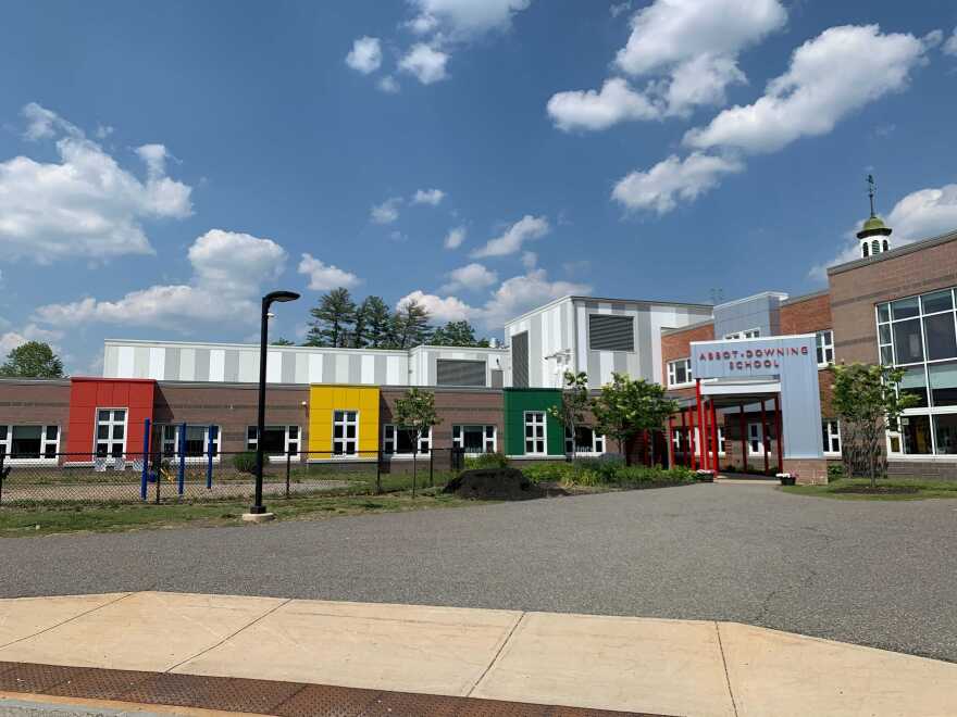 A red, green and yellow one story school building with a blue sky in the background. this is Abbot-Downing Elementary School in Concord.