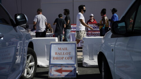 A sign indicates where mail ballots may be dropped off as people wait in line at one of a few in-person voting places during a nearly all-mail primary election in Las Vegas in a 2020 file photo.