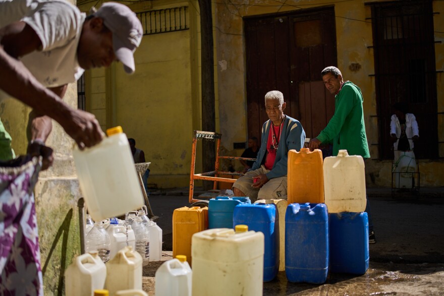A man fill containers with potable water during a blackout in Havana, Sunday, March 22, 2026.