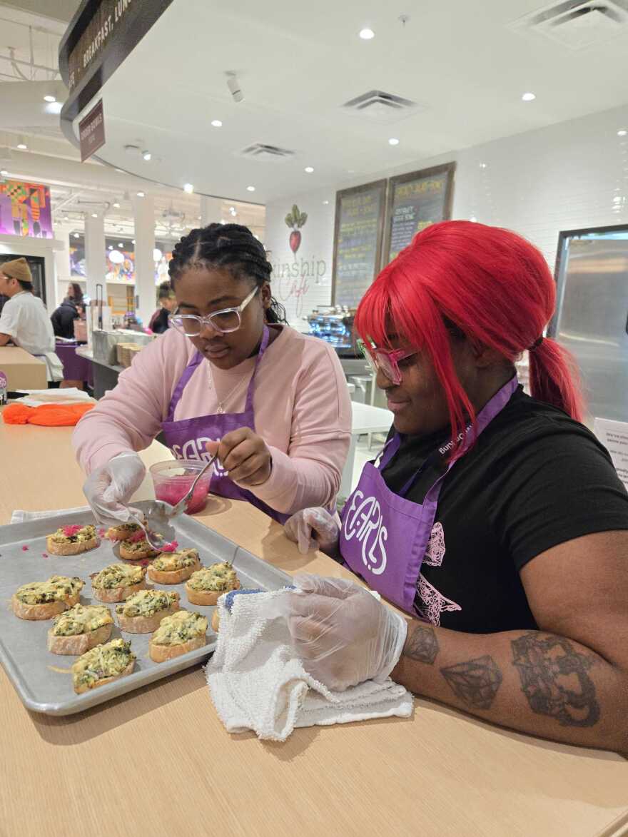 12-year-old Zuri Green plants dollops of picked onions onto crostinis as chef Shania Hutchins looks on.