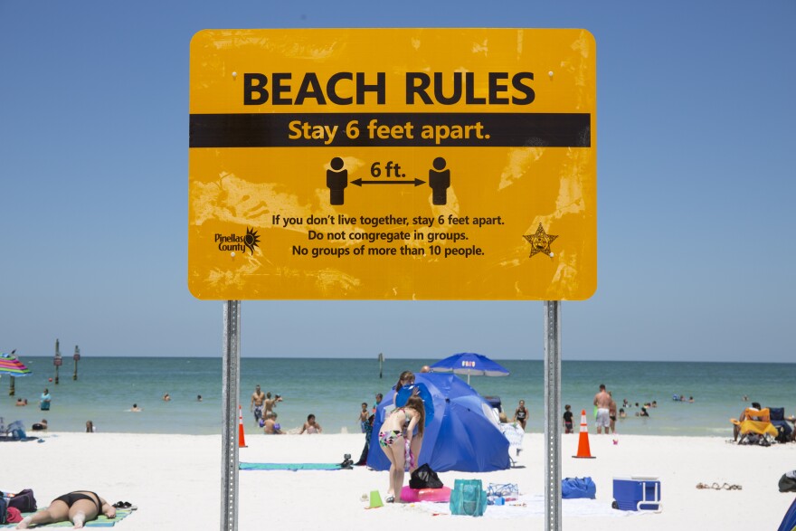 A sign on clearwater beach reminds people to follow social distancing guidelines by staying six feet apart