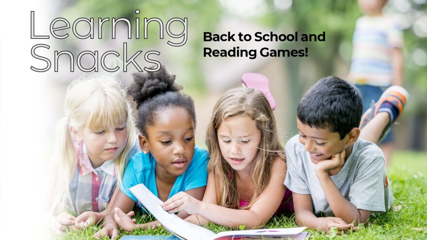 Group of 4 kids laying on a lawn and reading