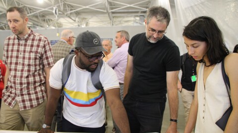A group of people look at a map, one man points at a point on the map.
