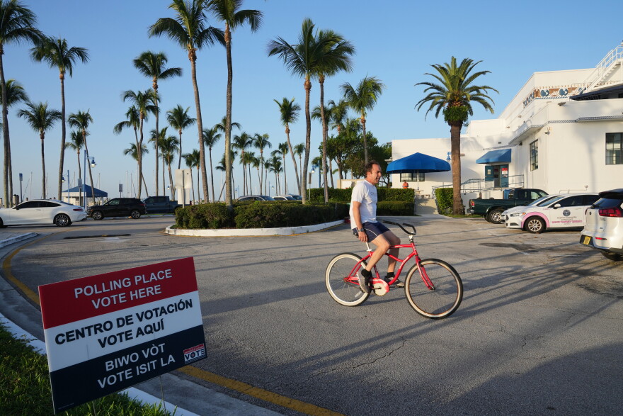 A cyclist rides past a voting precinct at Miami City Hall 