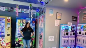 A woman stands in front of vending machines filled with Japanese food items.