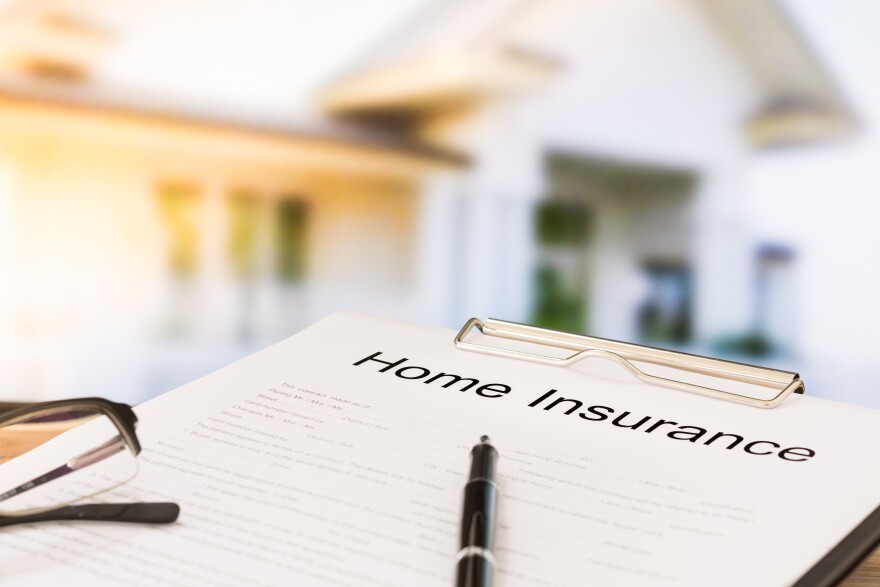 Insurance policy and a pen with home in background. Home insurance concepts.