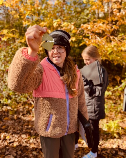 A Rockford Middle School student shows off a dogwood leaf during a phenology walk with John Latimer at the end of October, 2025.