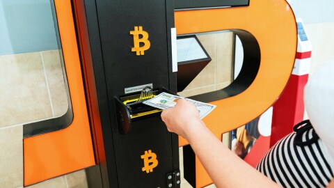 A person withdraws currency from a bitcoin ATM machine.