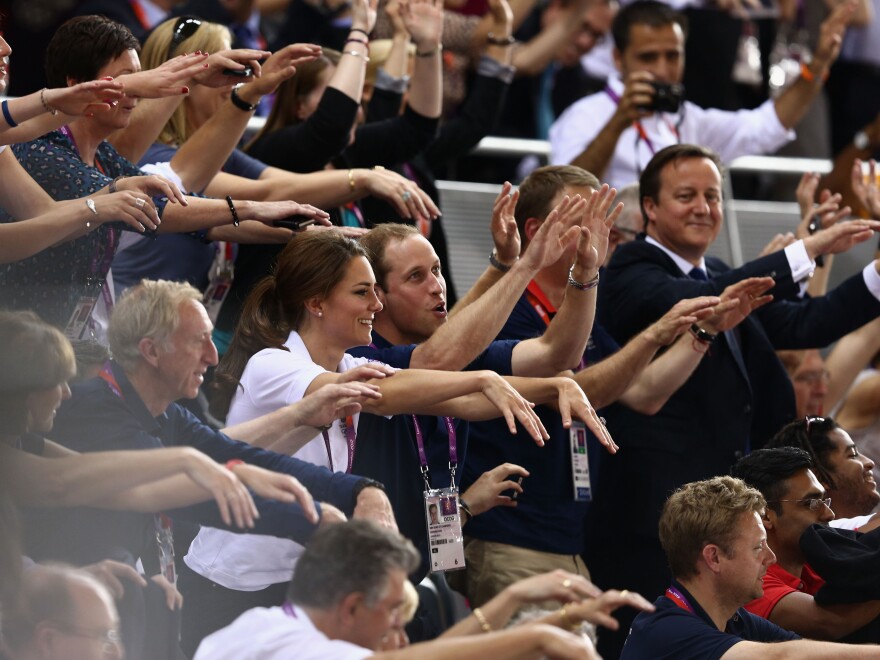 Prince William, his wife, Catherine, and Prime Minister David Cameron take part in the wave as they watch the track cycling at the London Games.