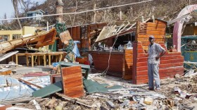 A man stands next to his business destroyed by Hurricane Beryl in St. Vincent.