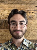 Head shot of a young man with short dark hair, glasses, and a beard.