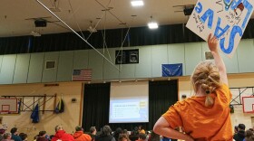 A young Larson Elementary School student holds up a "Save Larson" sign during a rally at Larson Elementary School on March 2, 2026.