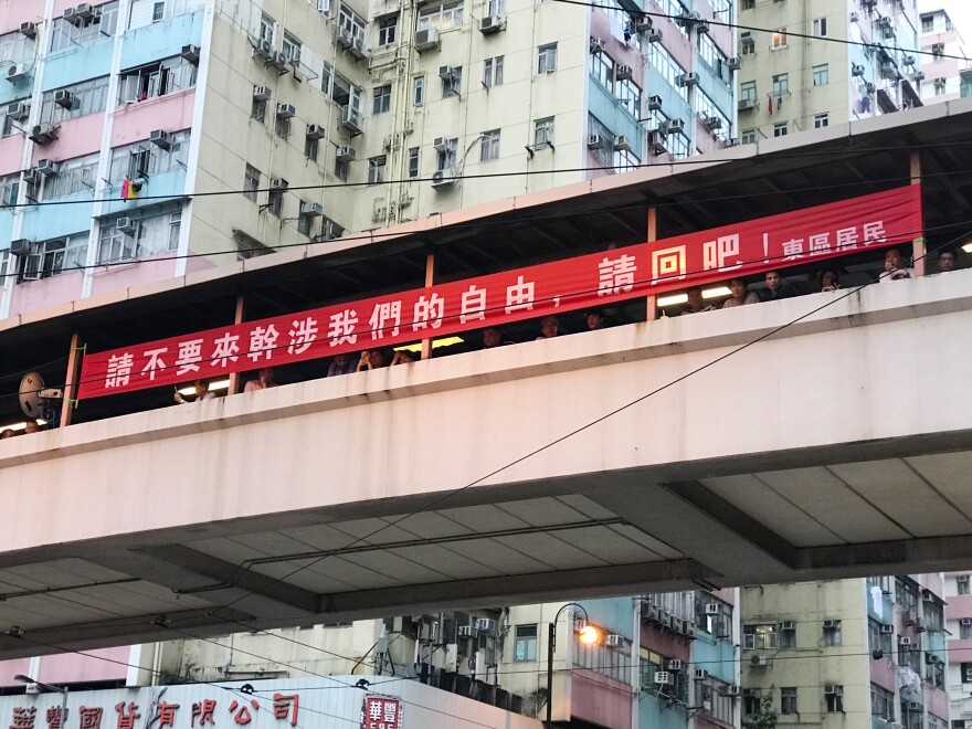 A banner hanging above King's Road in Hong Kong's North Point district tells protesters, "Please do not interfere with our liberties, please go back."