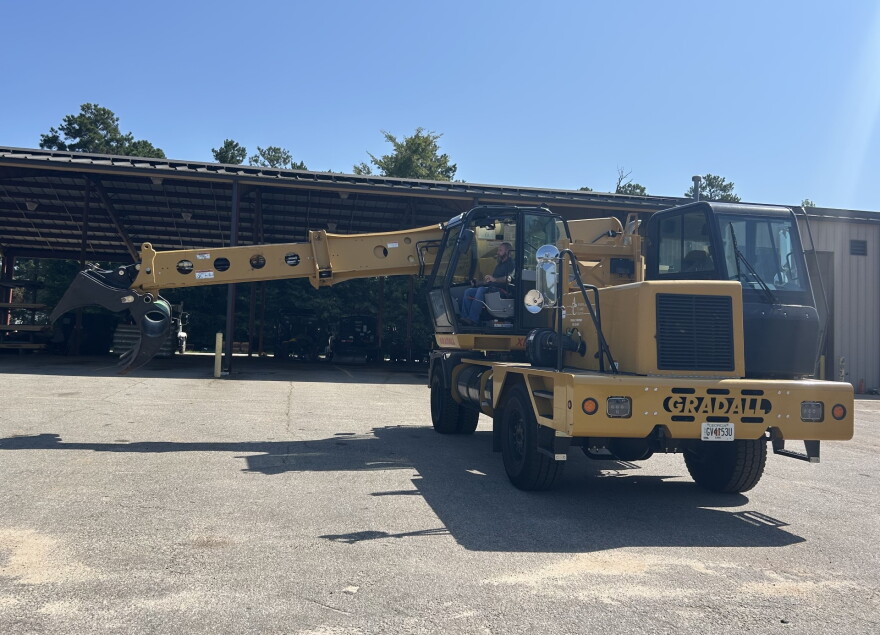 A large yellow construction vehicle with a man sitting inside.