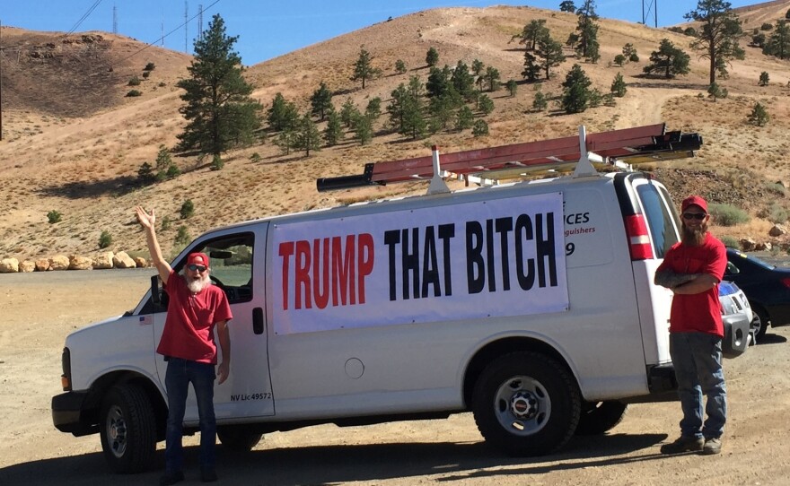Two men openly display an anti-Hillary Clinton banner with an expletive on it stretched across their white van on the side of a road in Reno, Nev., near a Clinton rally in August.