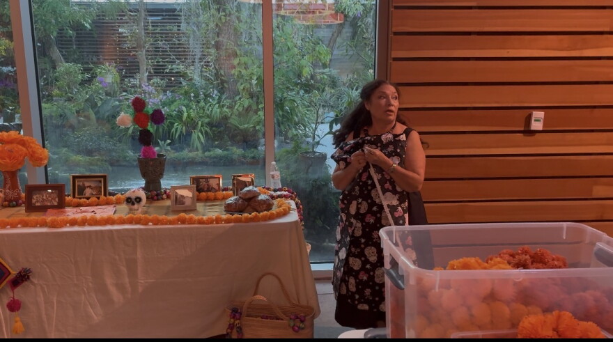 Maria Leticia Murillo Flood adds marigolds, known in Spanish as cempasúchil, to her ofrenda, or altar, on Oct. 30, 2026, at Naples Botanical Garden in Naples, Fla.