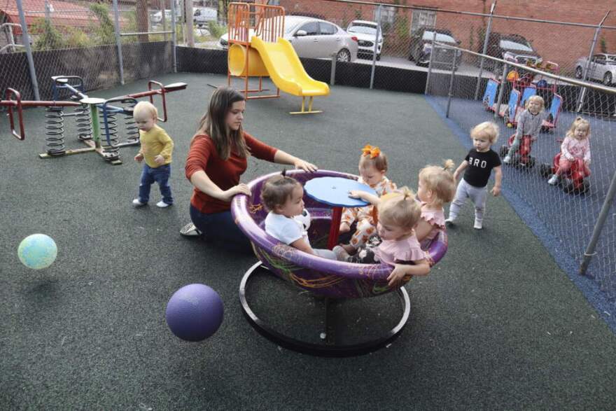 Day care staff member pushes toddlers on a teacup merry-go-round playground toy. (Leah Willingham/AP)