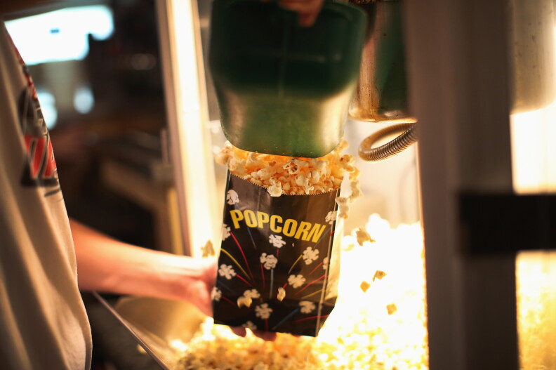 A person holds a popcorn back in popcorn machine.