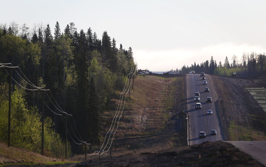 A convoy of cars sporadically heads south on Highway 63 on Friday after evacuees were stranded at an oil sands camp north of Fort McMurray.