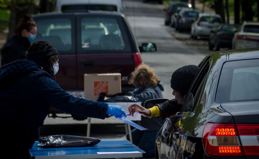 A staff member gives out tablets to parents at Mann Elementary School in St. Louis Tuesday, April 14, 2020, as St. Louis Public Schools ramps up remote learning for the extended school closure.