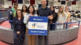 KUNR's Youth Media Coordinator Maria Palma pictured holding a WCSD student intern host sign with Work-Based Learning Coordinator, Crystal Edwards (left), and Reno High School Multimedia Teacher, Mr. Brian La Torre (right).