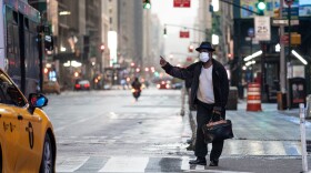 A man wearing a mask tries to catch a taxi at Times Square amid the Covid-19 pandemic on April 30, 2020 in New York City. (JOHANNES EISELE/AFP via Getty Images)