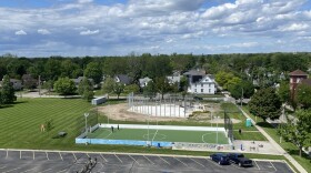 An asphalt parking lot, a soccer field, and an in construction baseball stadium lie next to a grassy field.