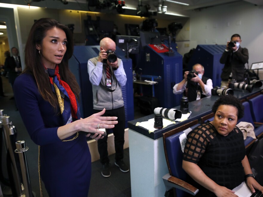 PBS reporter Yamiche Alcindor, seated, watches as One America News (OAN) White House Correspondent Chanel Rion asks a question of President Donald Trump during a briefing about the coronavirus in the James Brady Press Briefing Room of the White House, Monday, April 20, 2020, in Washington. (AP Photo/Alex Brandon)