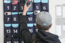 A ninth grader places his cellphone into a phone holder as he enters class at Delta High School, Friday, Feb. 23, 2024, in Delta, Utah. At the rural Utah school, there is a strict policy requiring students to check their phones at the door when entering every class. Each classroom has a cellphone storage unit that looks like an over-the-door shoe bag with three dozen smartphone-sized slots. 