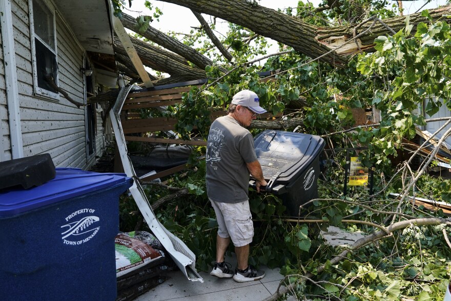 A man helps clear debris from the backyard of a damaged house after a tornado hit the day before, Tuesday, July 28, 2026, in Appleton, Wis. (AP Photo/Kayla Wolf)