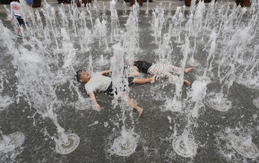 In this Aug. 8, 2019, photo, children cool off in an outdoor water fountain in Seoul, South Korea. A heat wave warning was issued in Seoul as temperatures soared above 32 degrees Celsius 